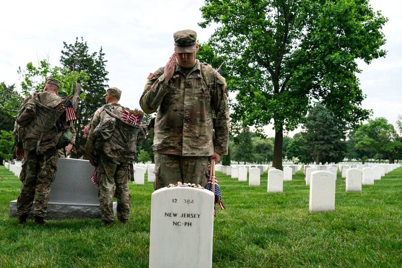 ARLINGTON, VIRGINIA - MAY 23: Members of the 3rd U.S. Infantry Regiment, also known as the "Old Guard," place flags at the headstones of U.S. military personnel buried at Arlington National Cemetery ahead of Memorial Day, on May 23, 2024 in Arlington, Virginia. Nearly 1,500 joint service members will spend around four hours placing small American flags in front of more than 260,000 headstones. The cemetery, consisting of 639 acres, is the final resting place of approximately 400,000 veterans and their dependents. (Photo by Kent Nishimura/Getty Images)